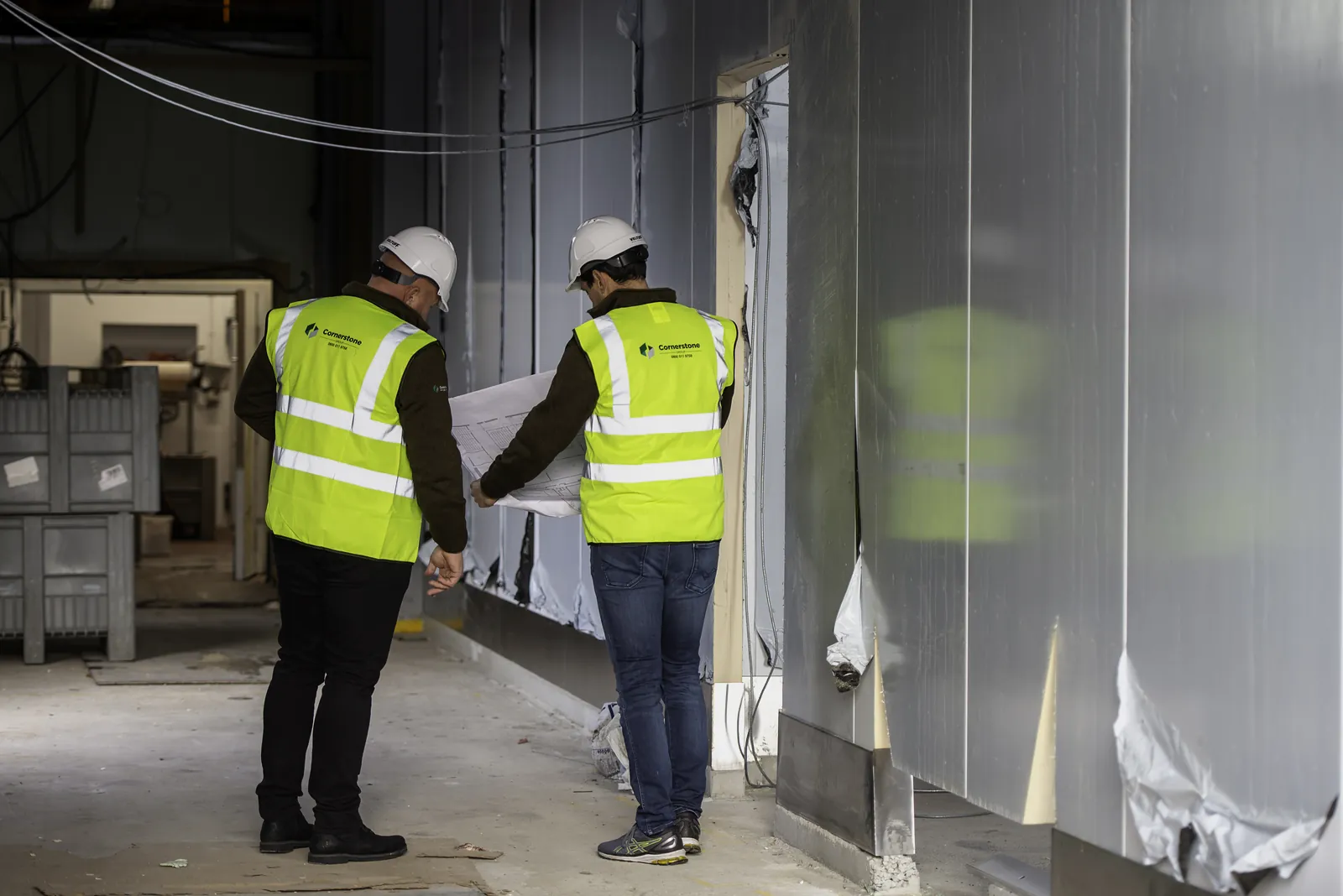 On site, reviewing drawings, hard hats on